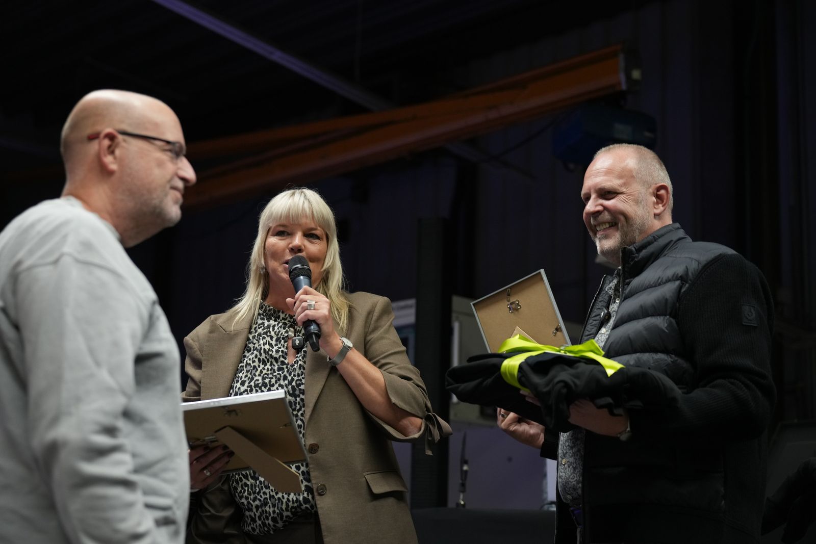 Petra Schneider spricht auf der B&uuml;hne, J&ouml;rg Schneider h&auml;lt ein Geschenk